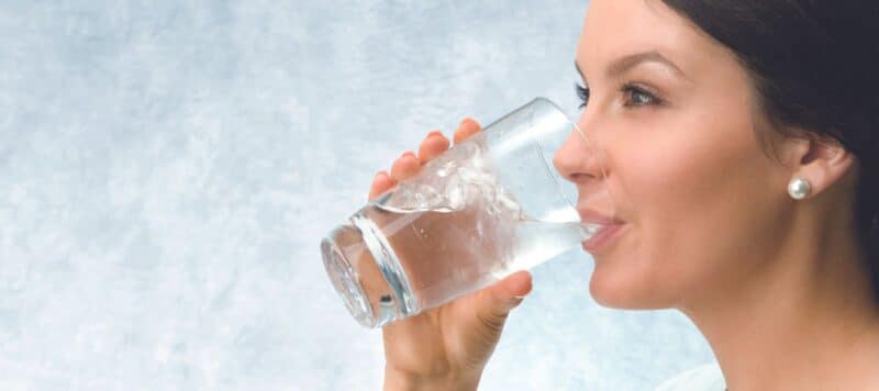 woman drinking clean, filtered water from a clear glass cup