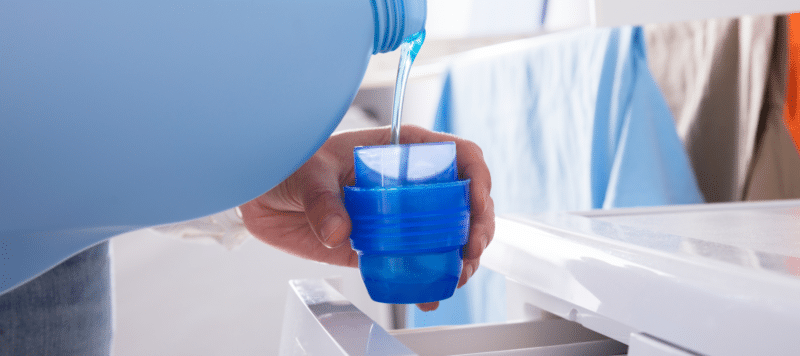 closeup of someone pouring laundry detergent in the cup