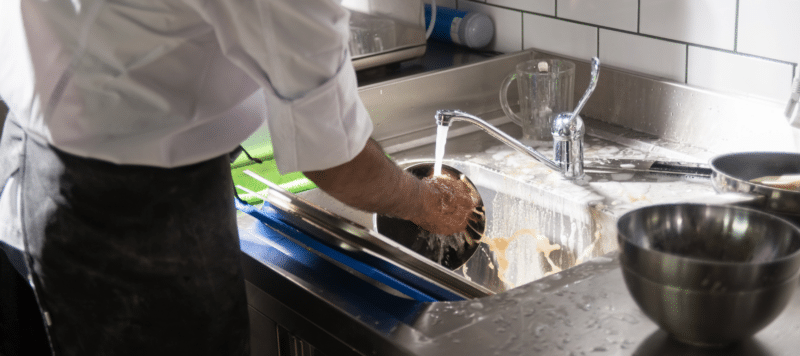 person washing dishes in a commercial restaurant setting