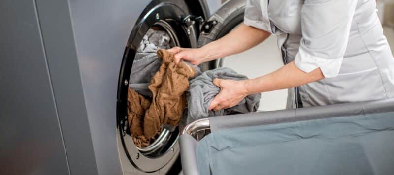 laundry woman at a hotel putting laundry in the washing machine