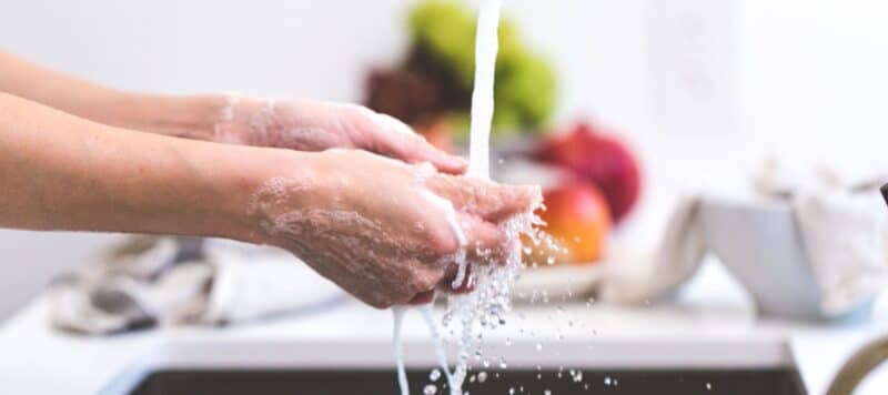 person washing hands in sink